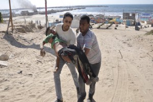 Palestinians carry the body of a boy, whom medics said was killed by a shell fired by an Israeli naval gunboat, on a beach in Gaza City